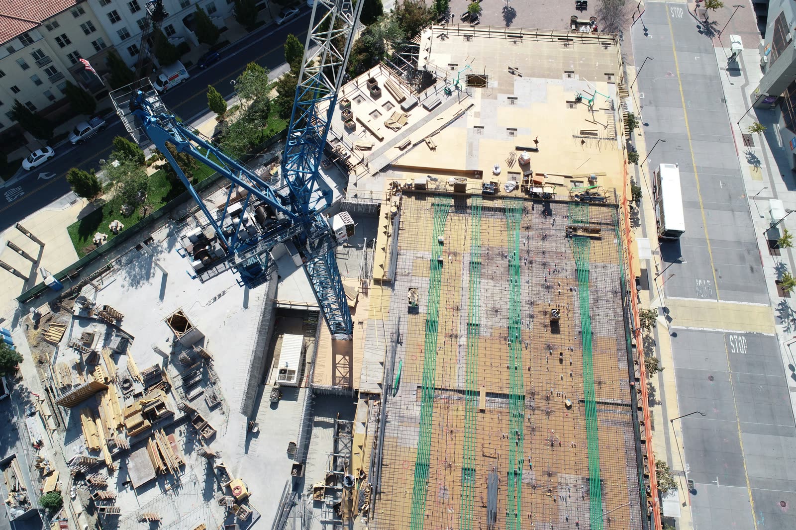 Aerial view of an active commercial construction site with tower crane and rebar decking