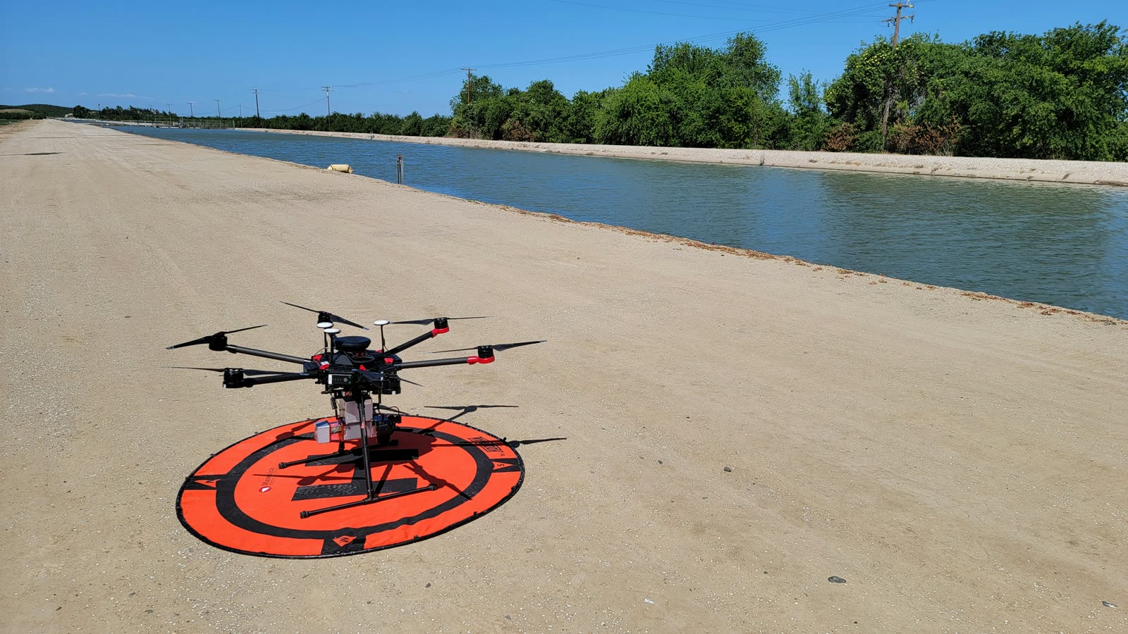 Survey drone staged on a landing pad beside a canal before an infrastructure mapping flight